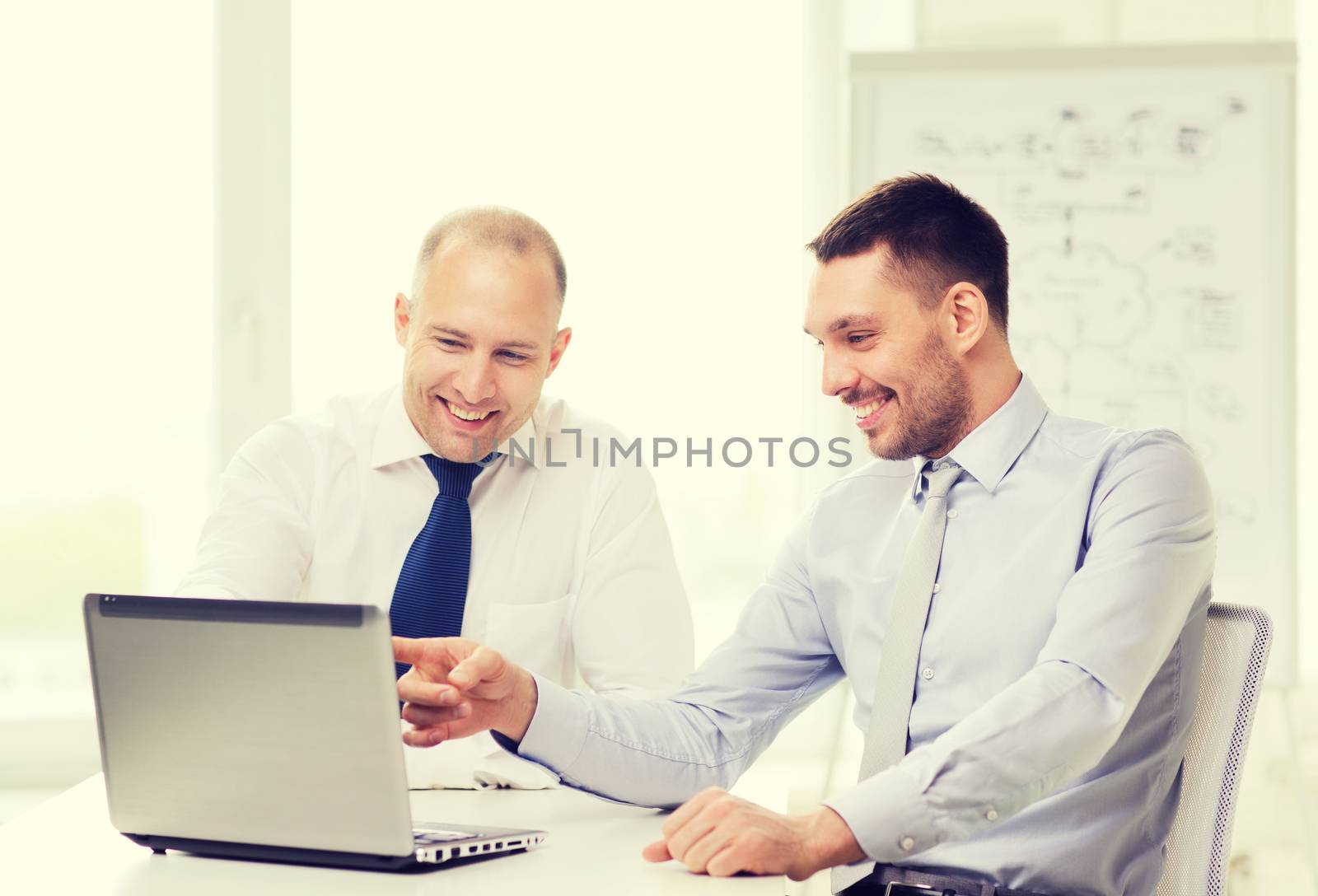 two smiling businessmen with laptop in office by dolgachov