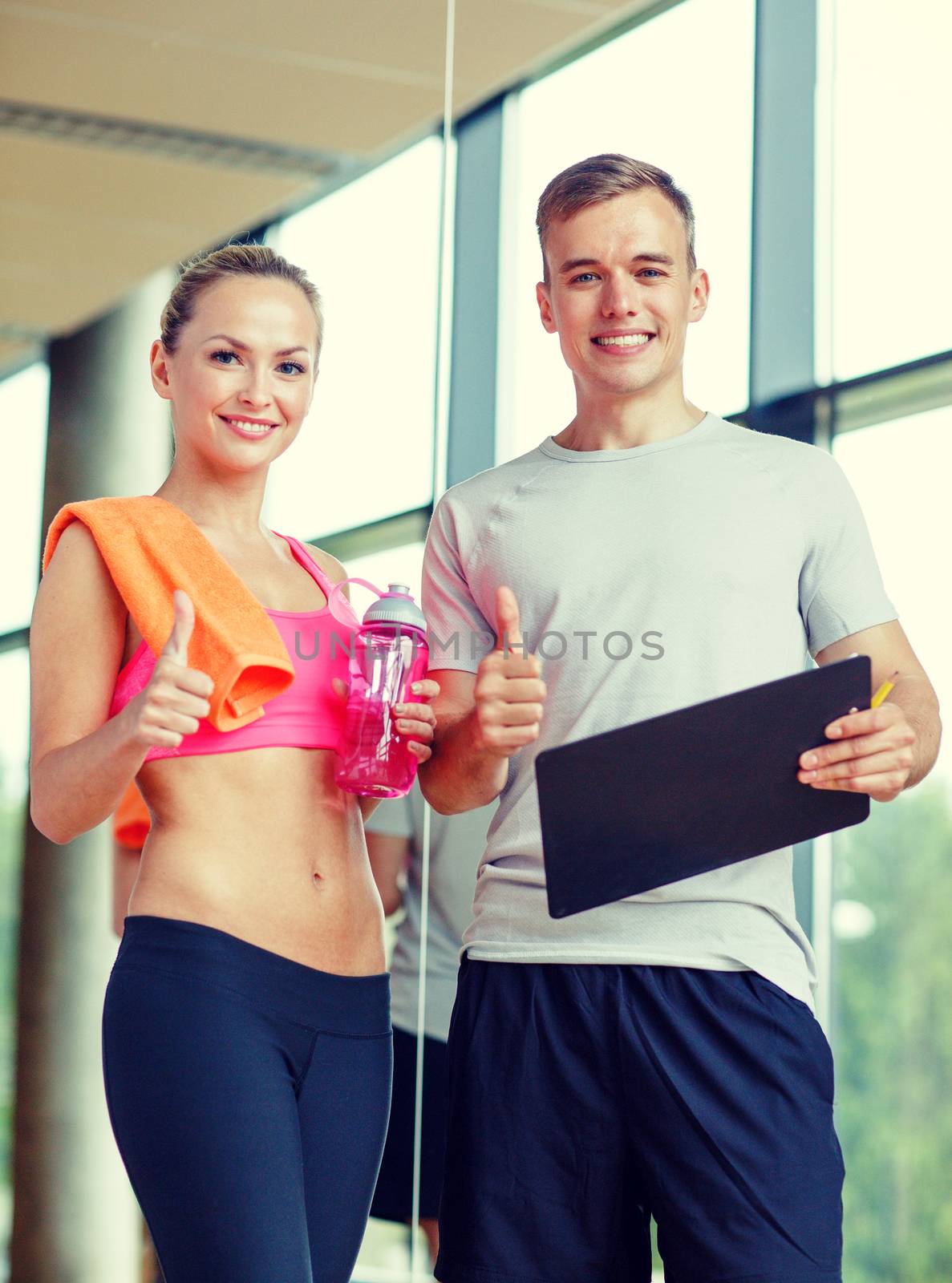 fitness, sport, exercising and diet concept - smiling young woman with personal trainer after training in gym showing thumb up