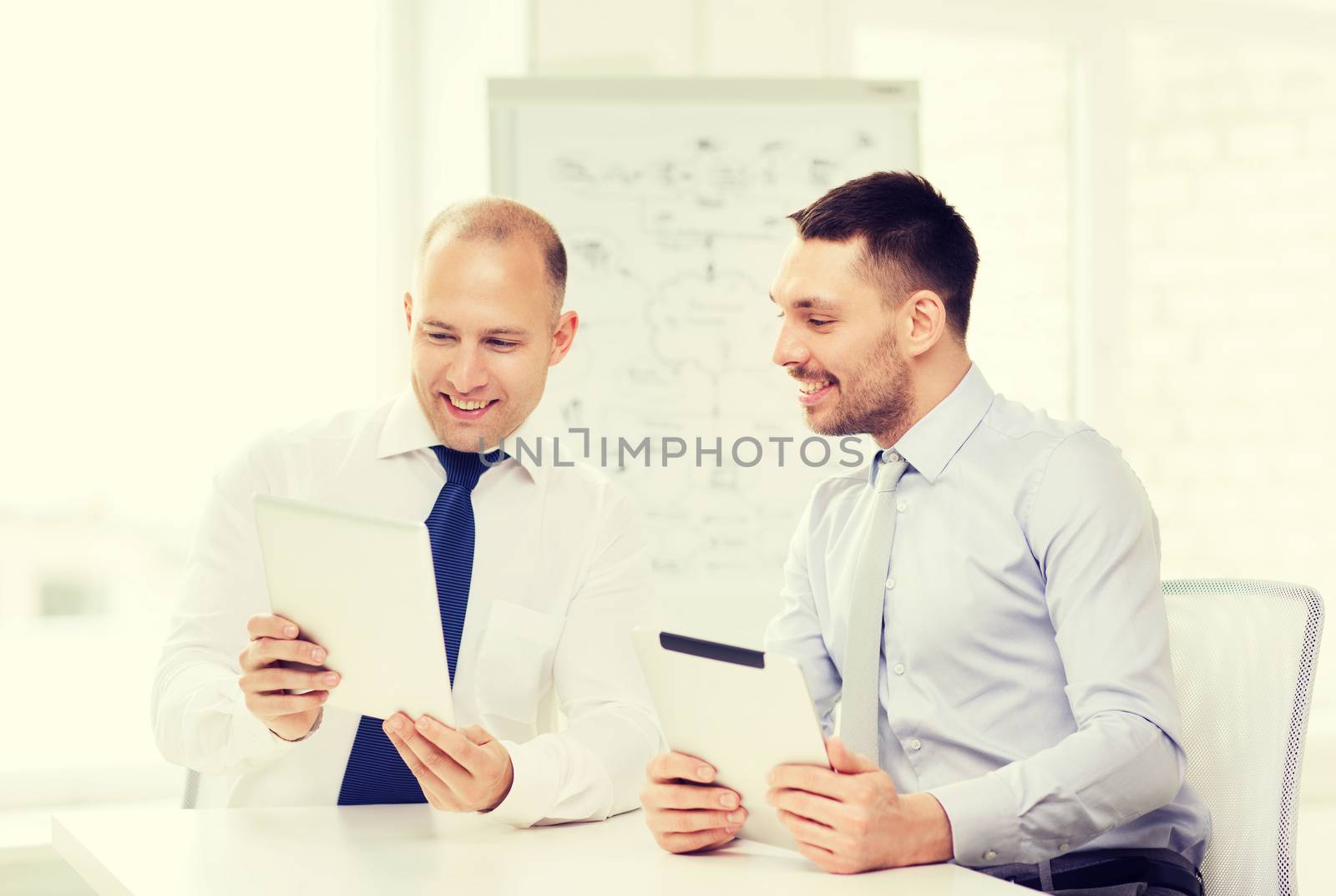 two smiling businessmen with tablet pc in office by dolgachov