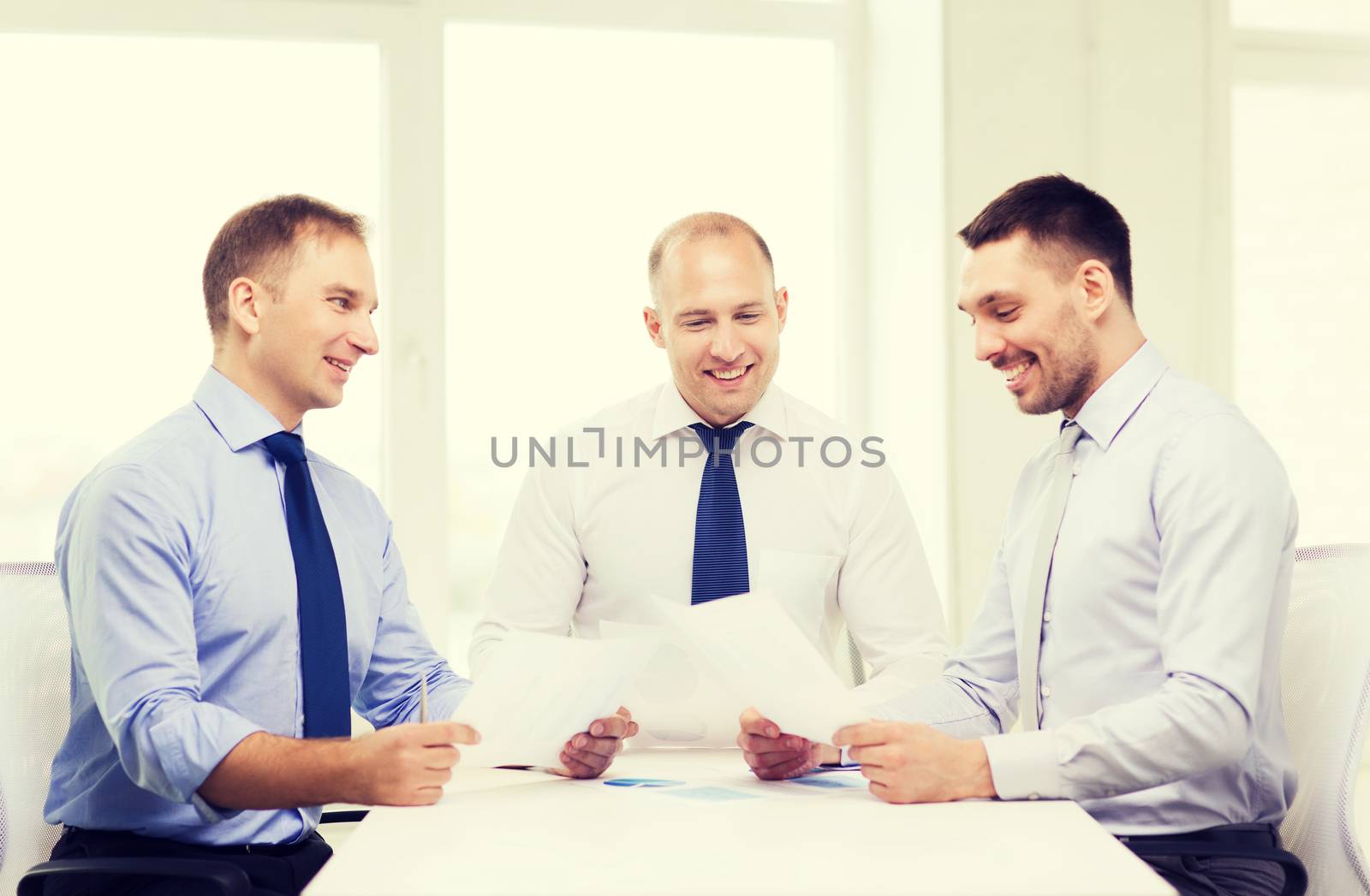 smiling businessmen with papers in office by dolgachov