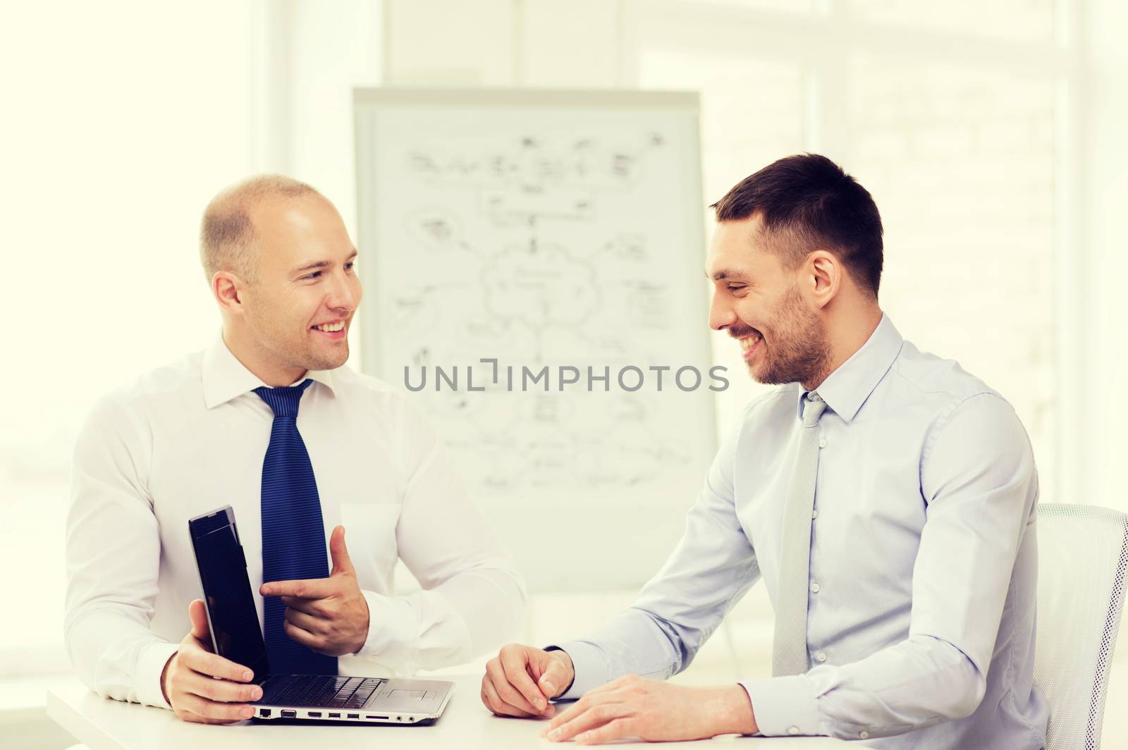 two smiling businessmen with laptop in office by dolgachov
