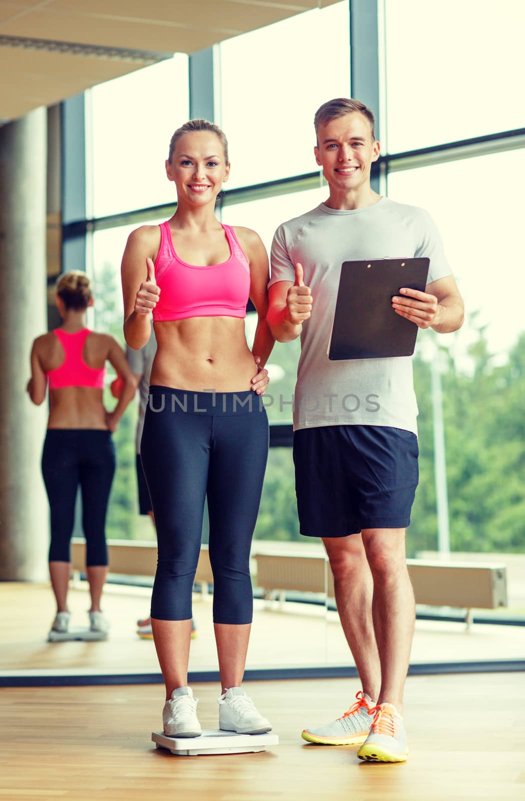 smiling man and woman with scales in gym by dolgachov
