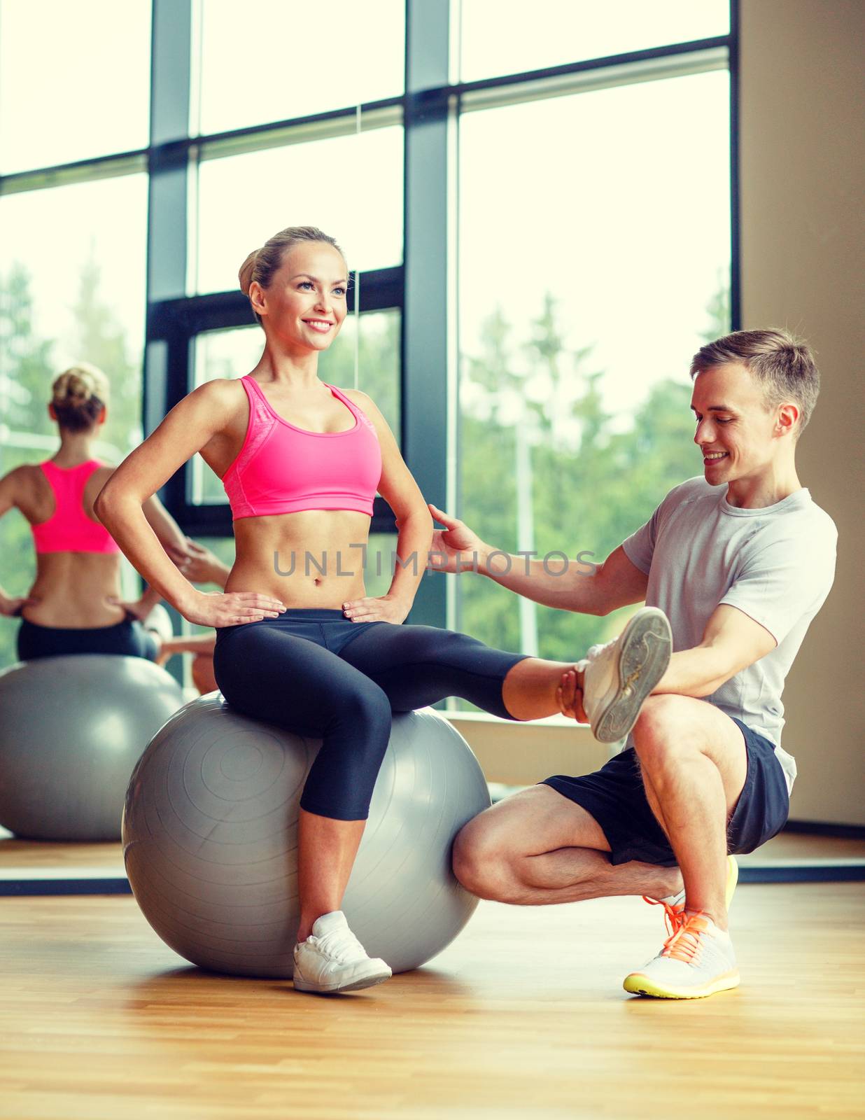 smiling man and woman with exercise ball in gym by dolgachov