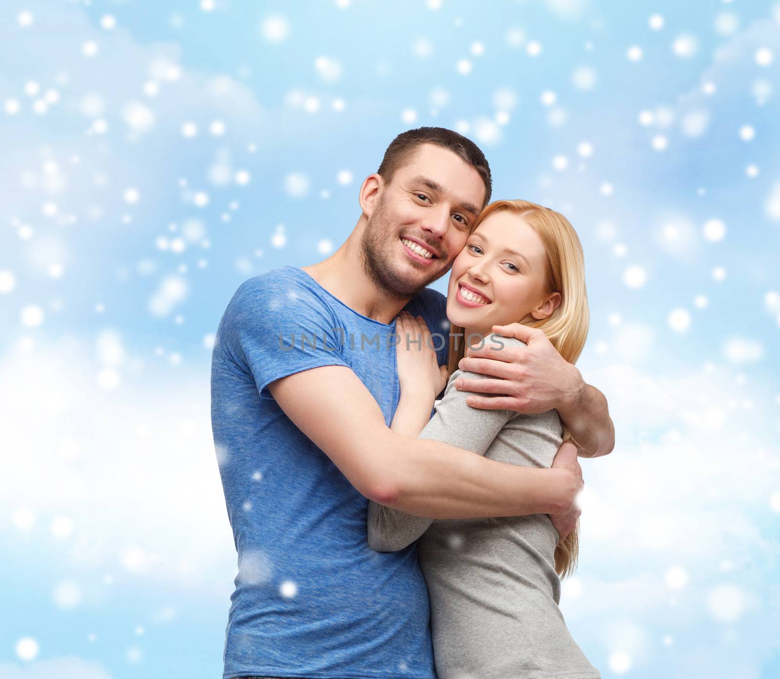 love, people and family concept - smiling couple hugging over blue sky, snow and cloud background