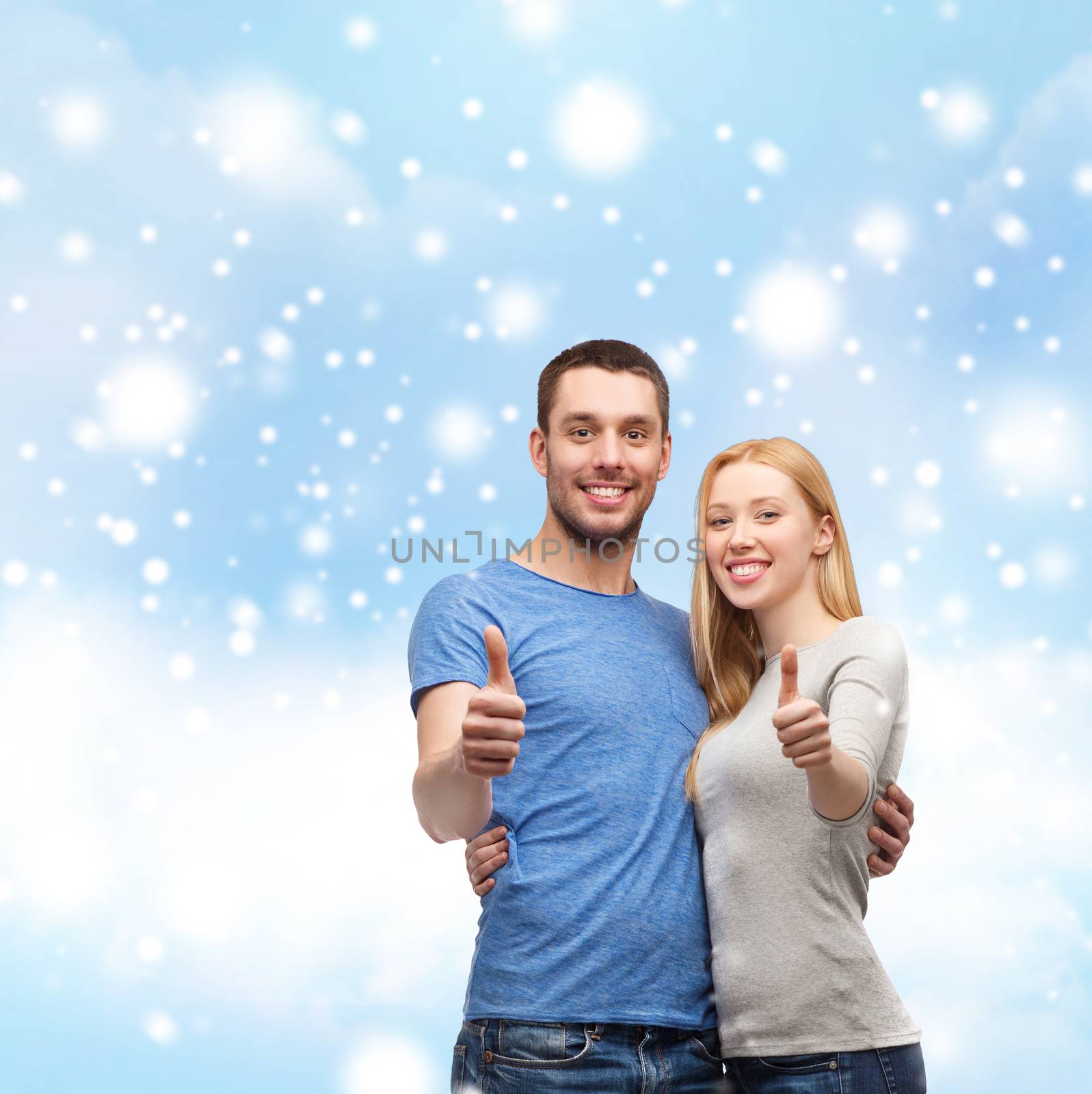 love, people and family concept - smiling couple snowing thumbs up gesture and hugging over blue sky with snow, cloud background