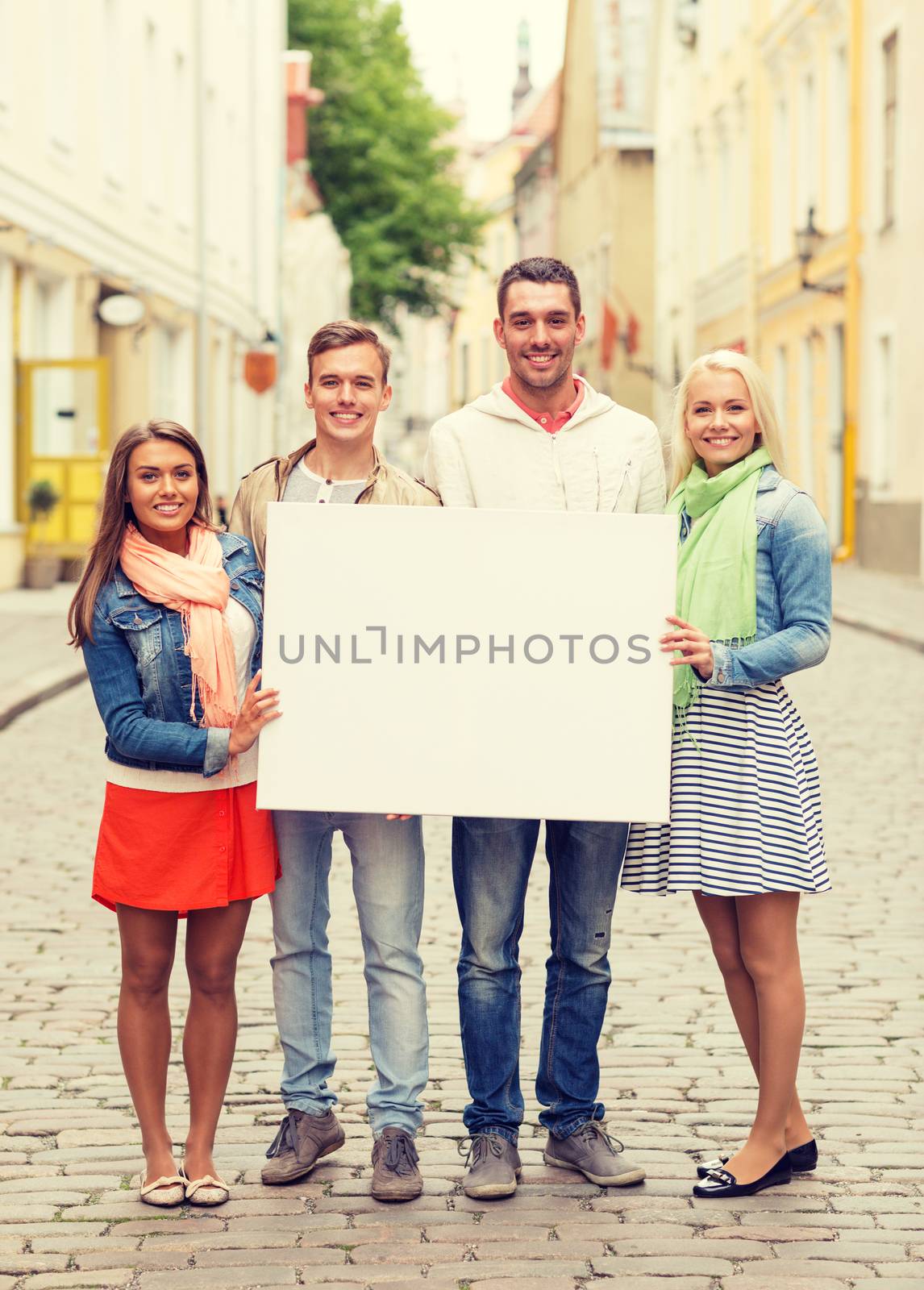 group of smiling friends with blank white board by dolgachov