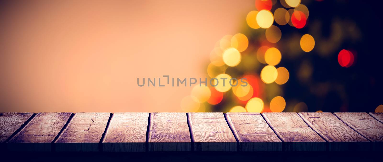 Wooden desk against desk with christmas tree in background