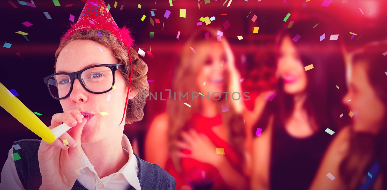 Geeky hipster wearing a party hat wig blowing party horn against pretty friends drinking cocktails together
