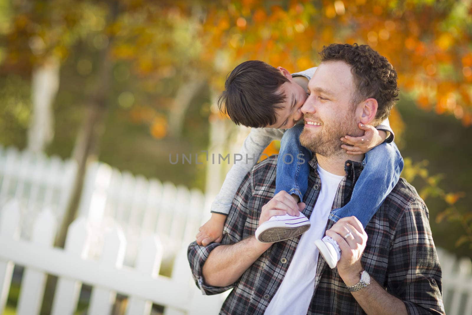 Happy Mixed Race Boy Riding Piggyback on Shoulders of Caucasian Father.