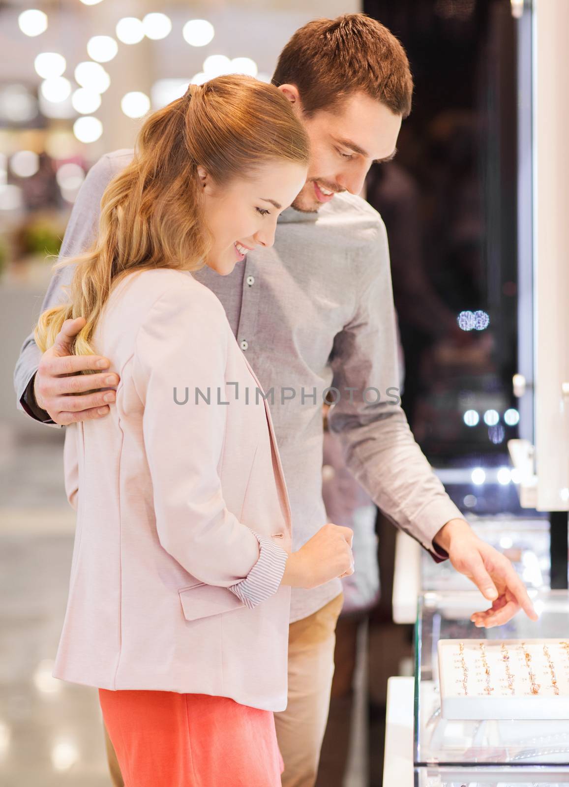 happy couple choosing engagement ring in mall by dolgachov