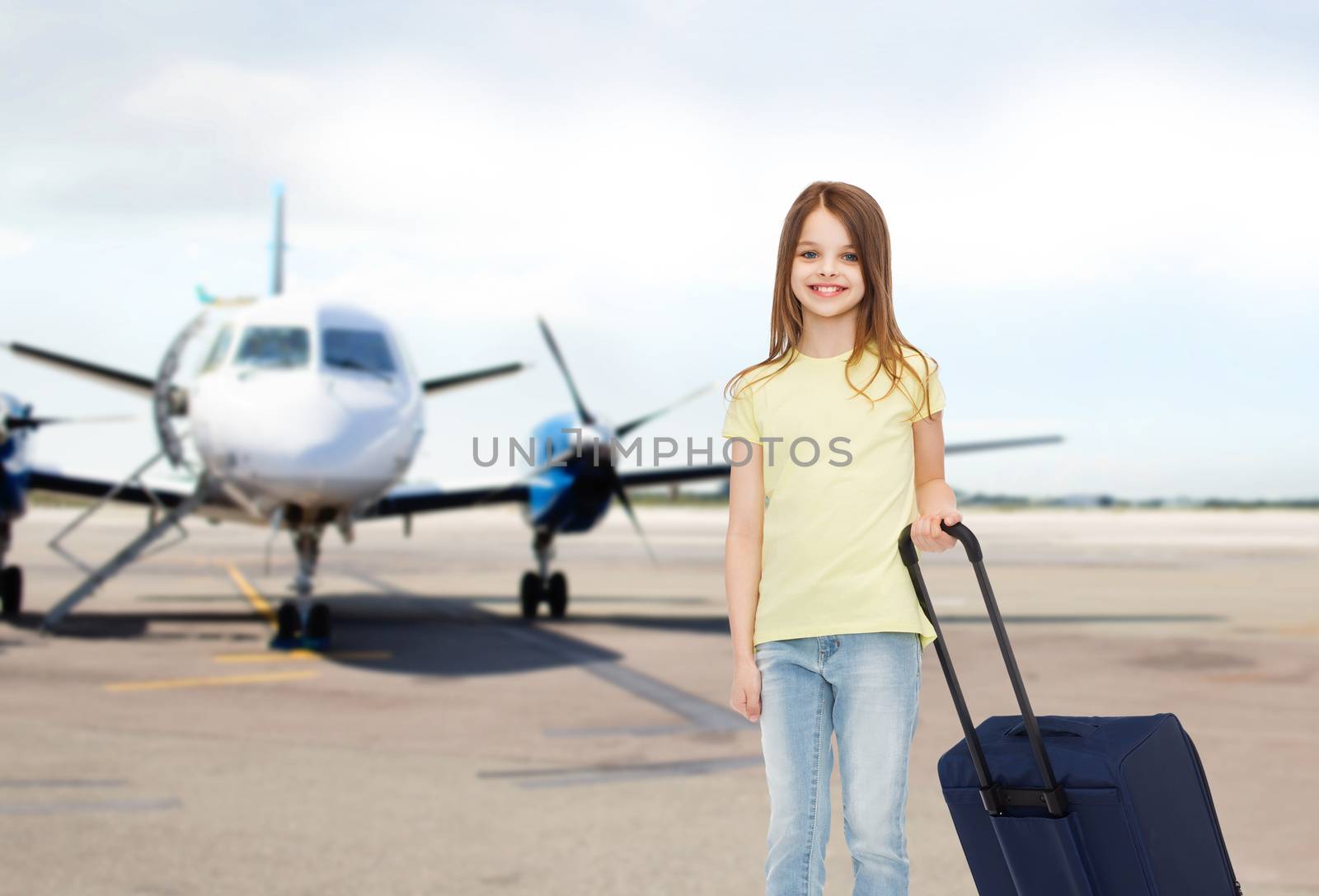 tourism, holiday, vacation, childhood and transportation concept - smiling little girl with travel bag over airport background