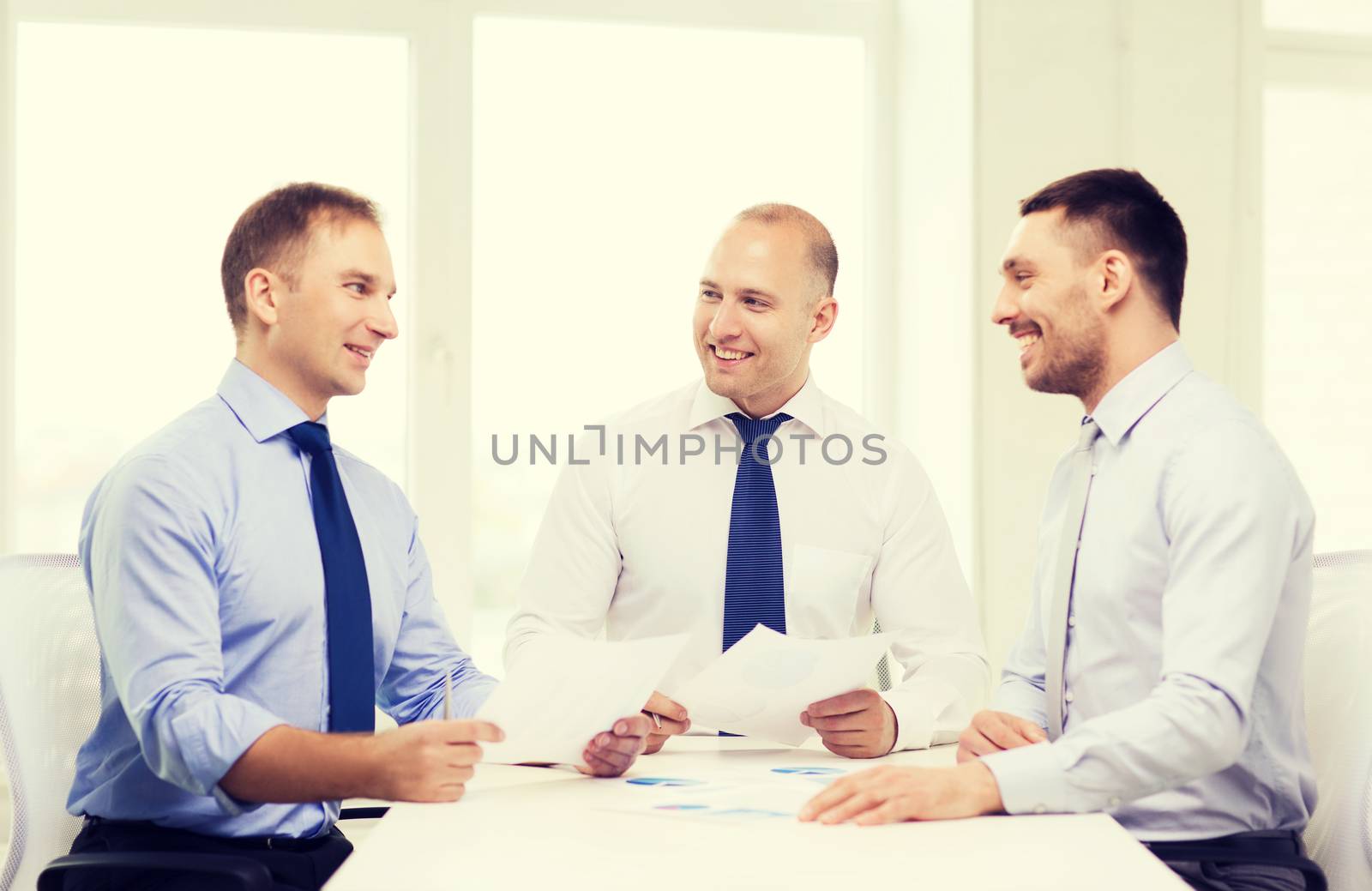 smiling businessmen with papers in office by dolgachov