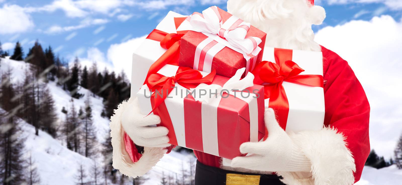 christmas, holidays and people concept - close up of santa claus with gift box over snowy mountains