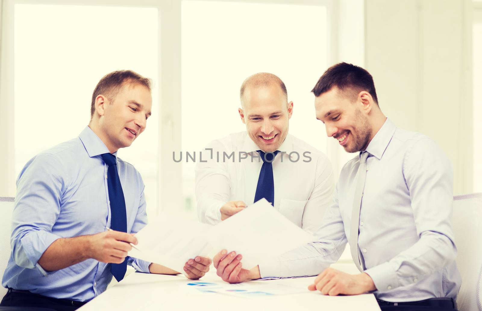 smiling businessmen with papers in office by dolgachov