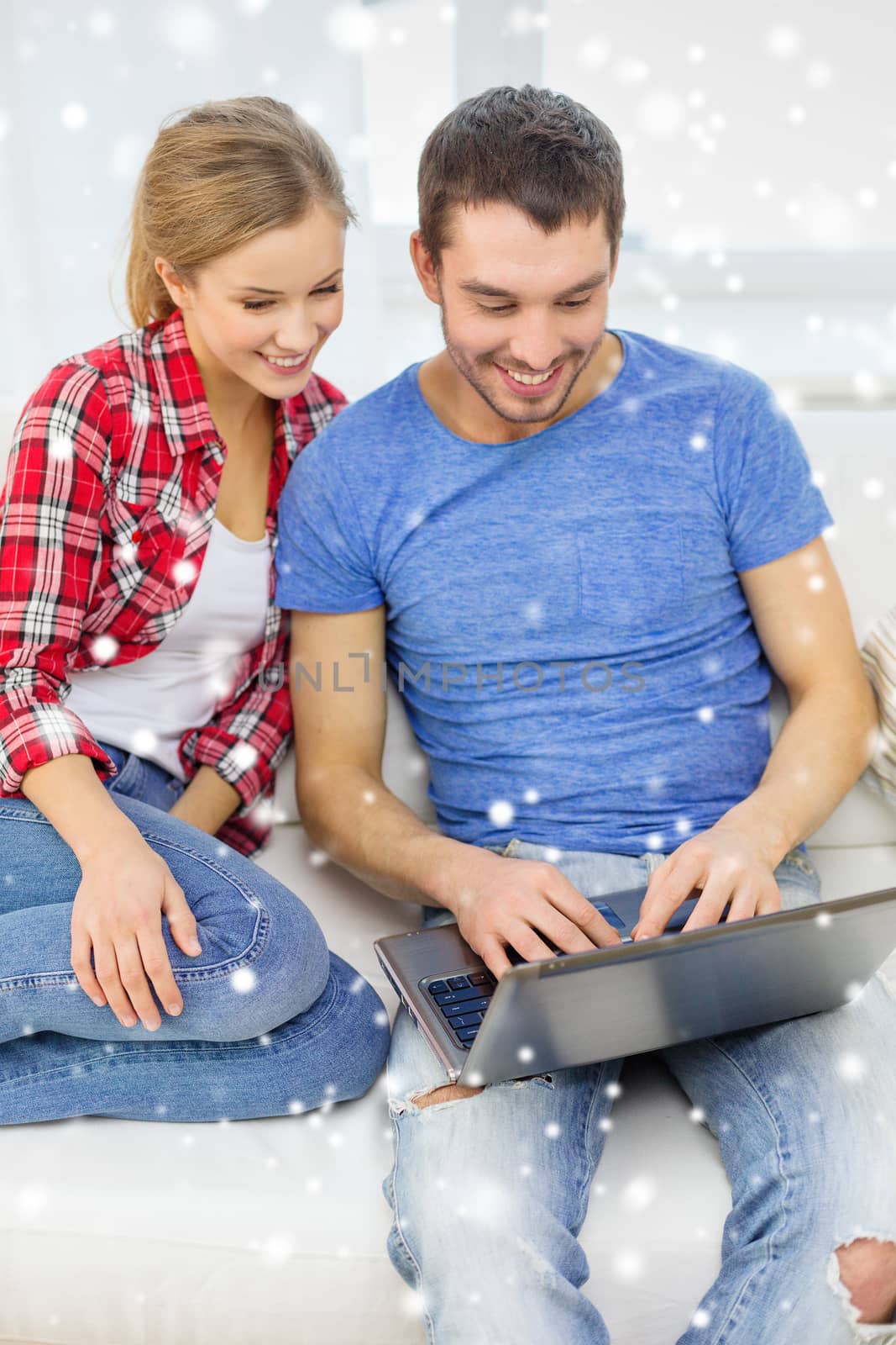 technology, people and relationships concept - smiling couple with laptop computer sitting on sofa at home