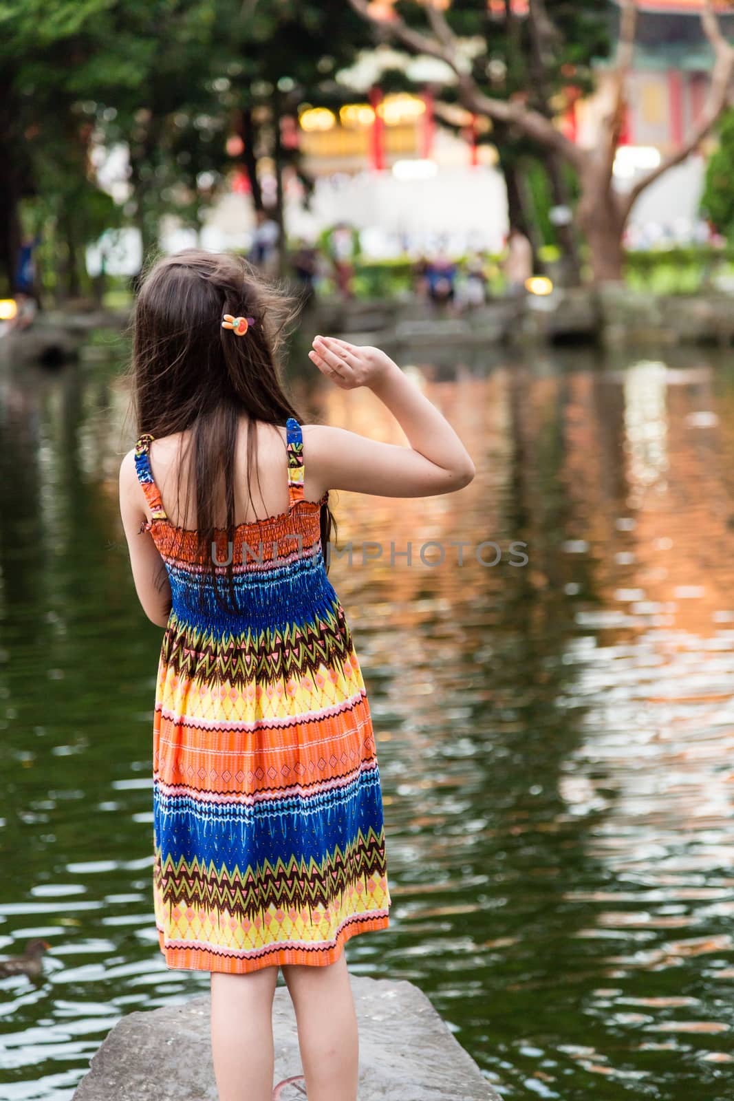Young girl in colorful dress by lake