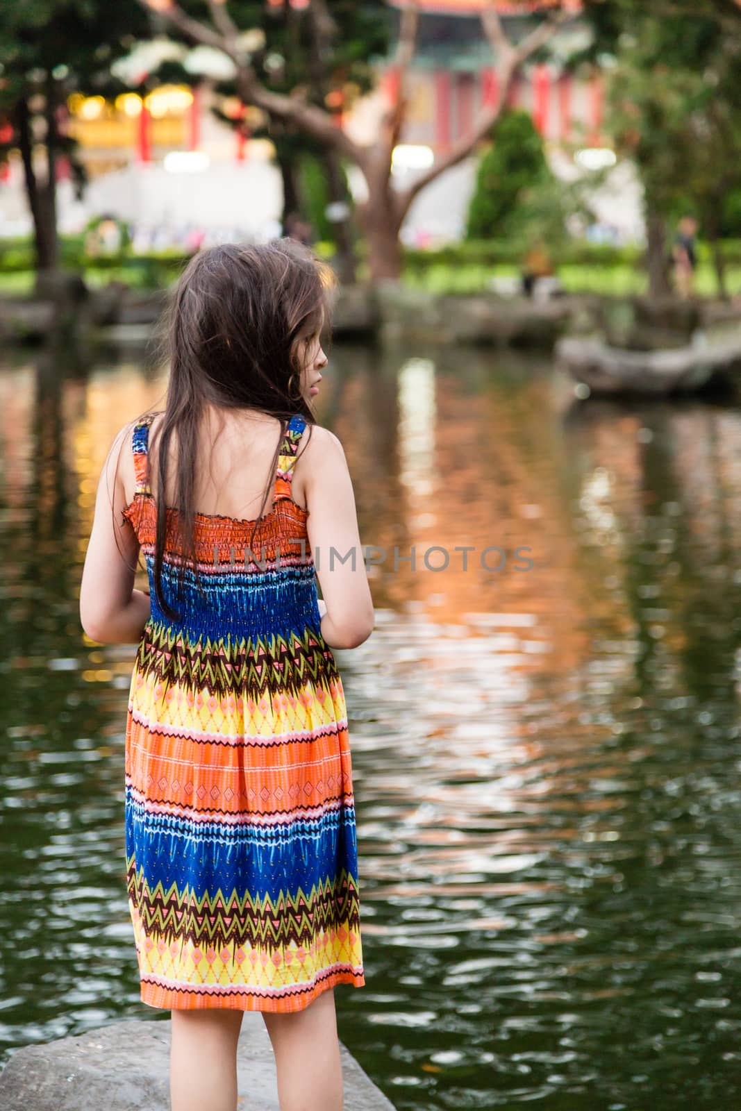Young girl in colorful dress by lake