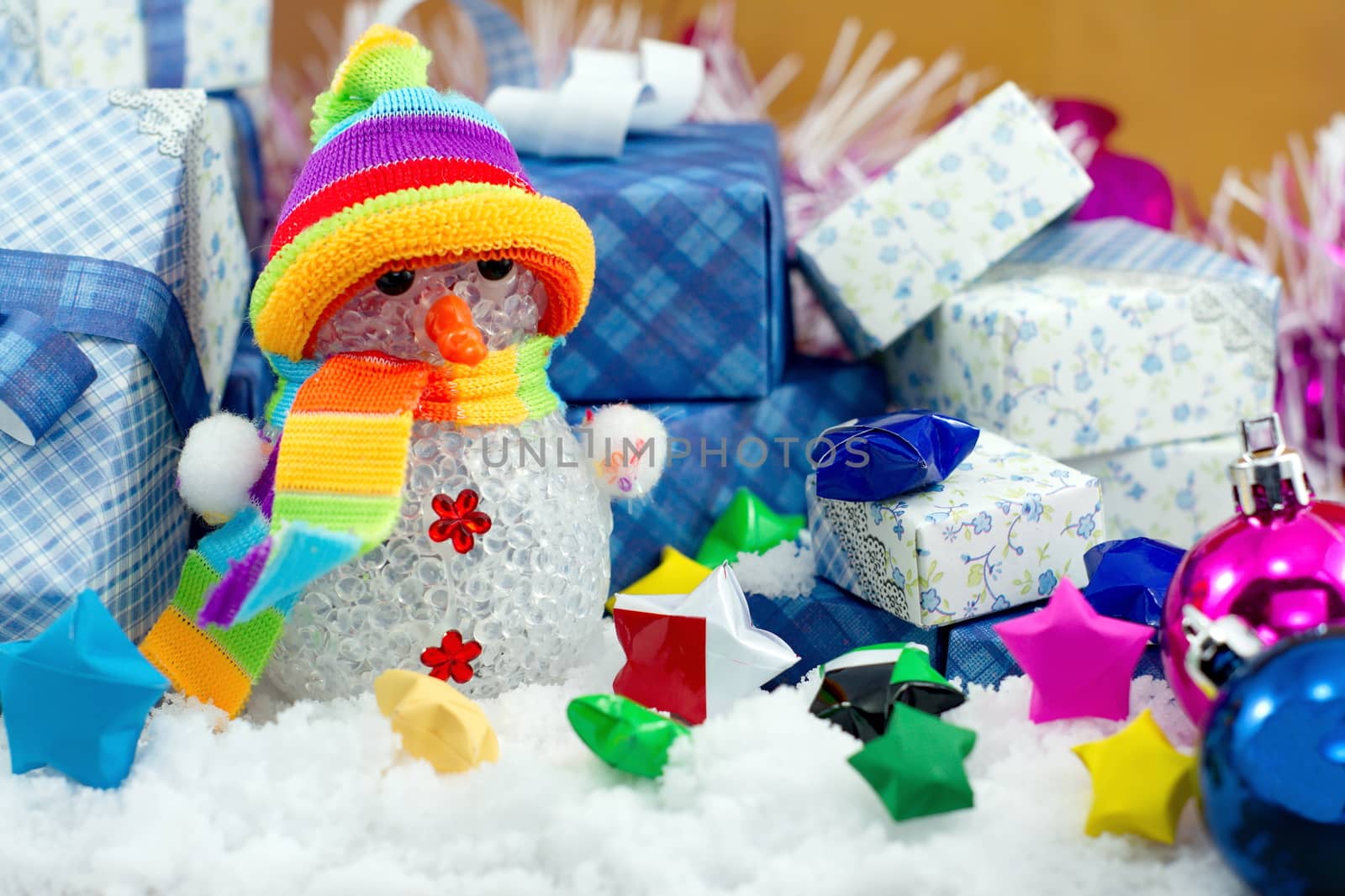 Snowman and gift box with small star paper on the snow field.