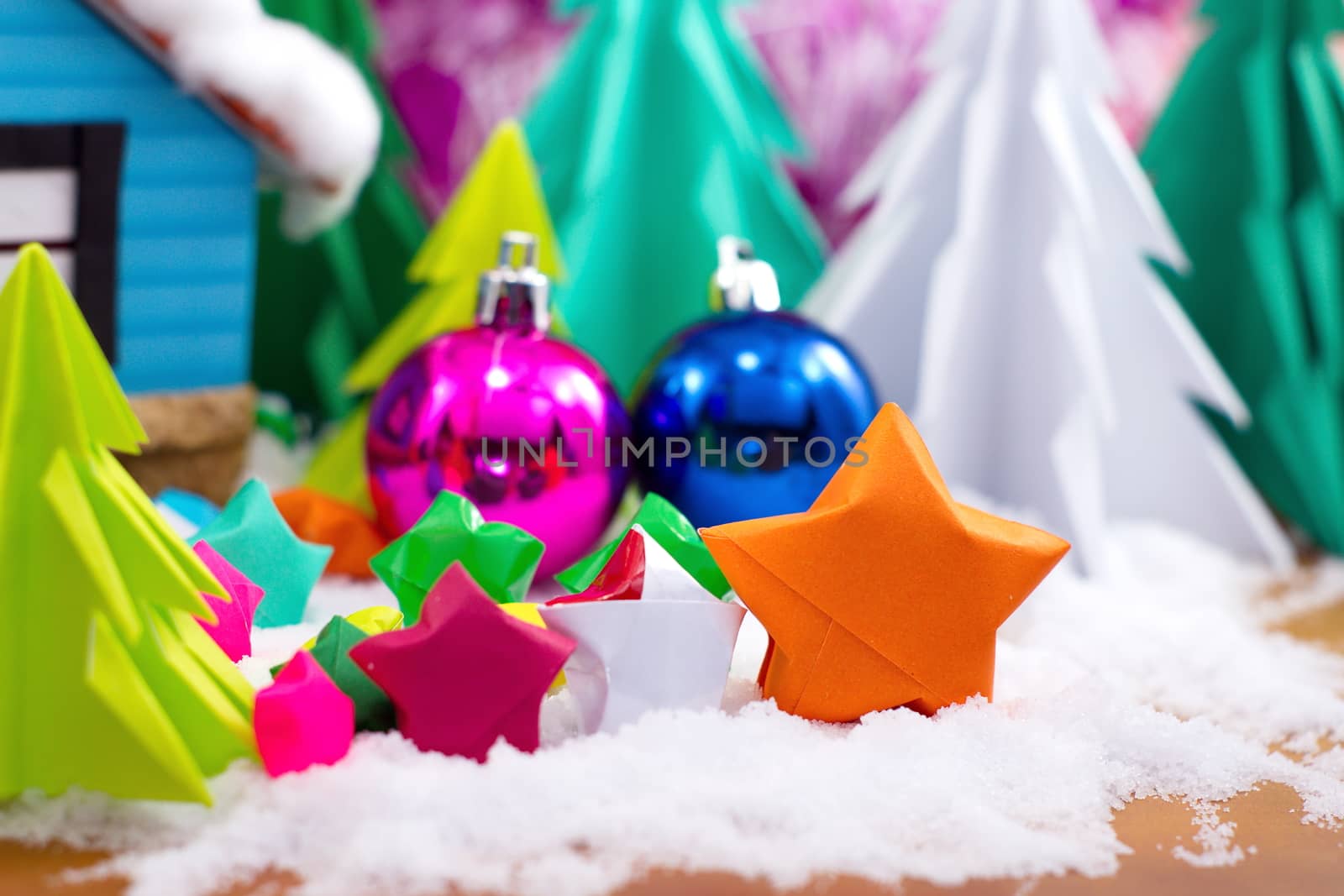 multicolor star folded paper on snow. with christmas ball and tree background