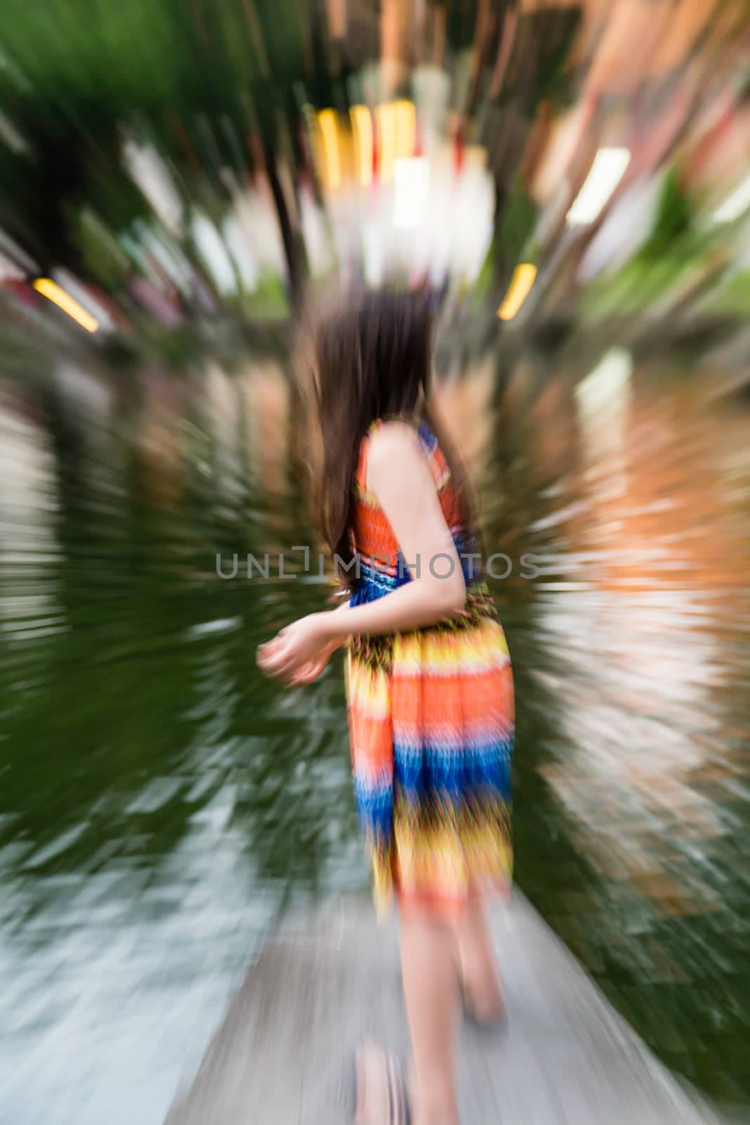 Young girl in colorful dress by lake, defocused