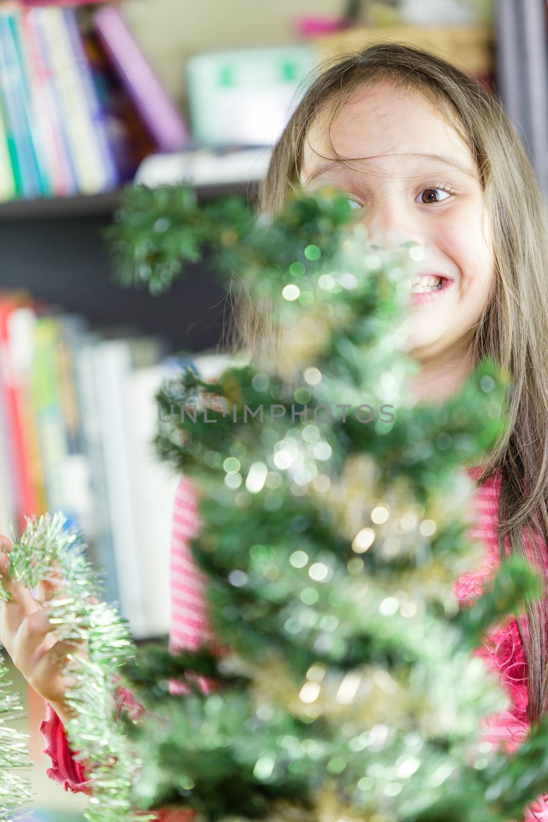 Young girl happily decorating Christmas tree