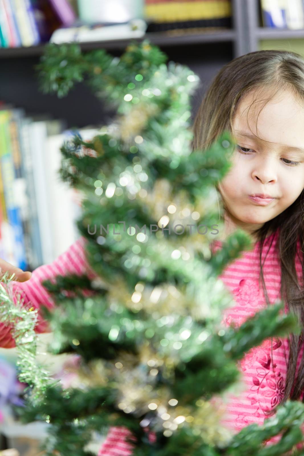 Young girl happily decorating Christmas tree