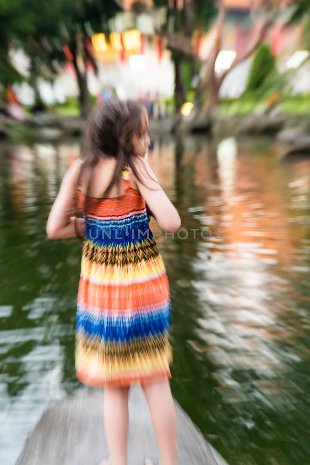 Young girl in colorful dress by lake, defocused