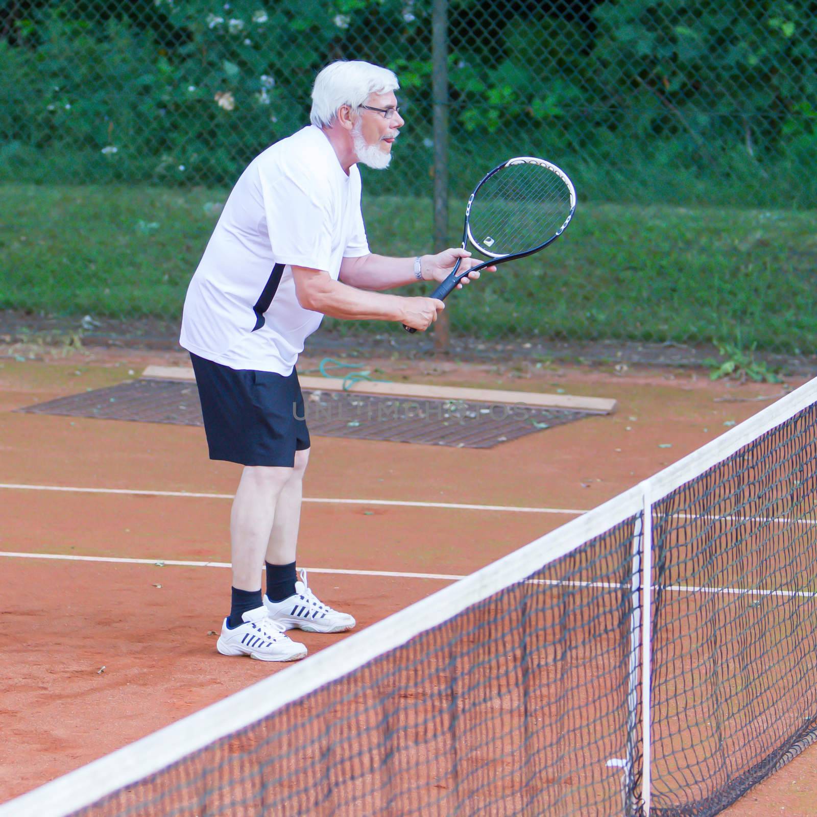 Senior man playing tennis by michaklootwijk