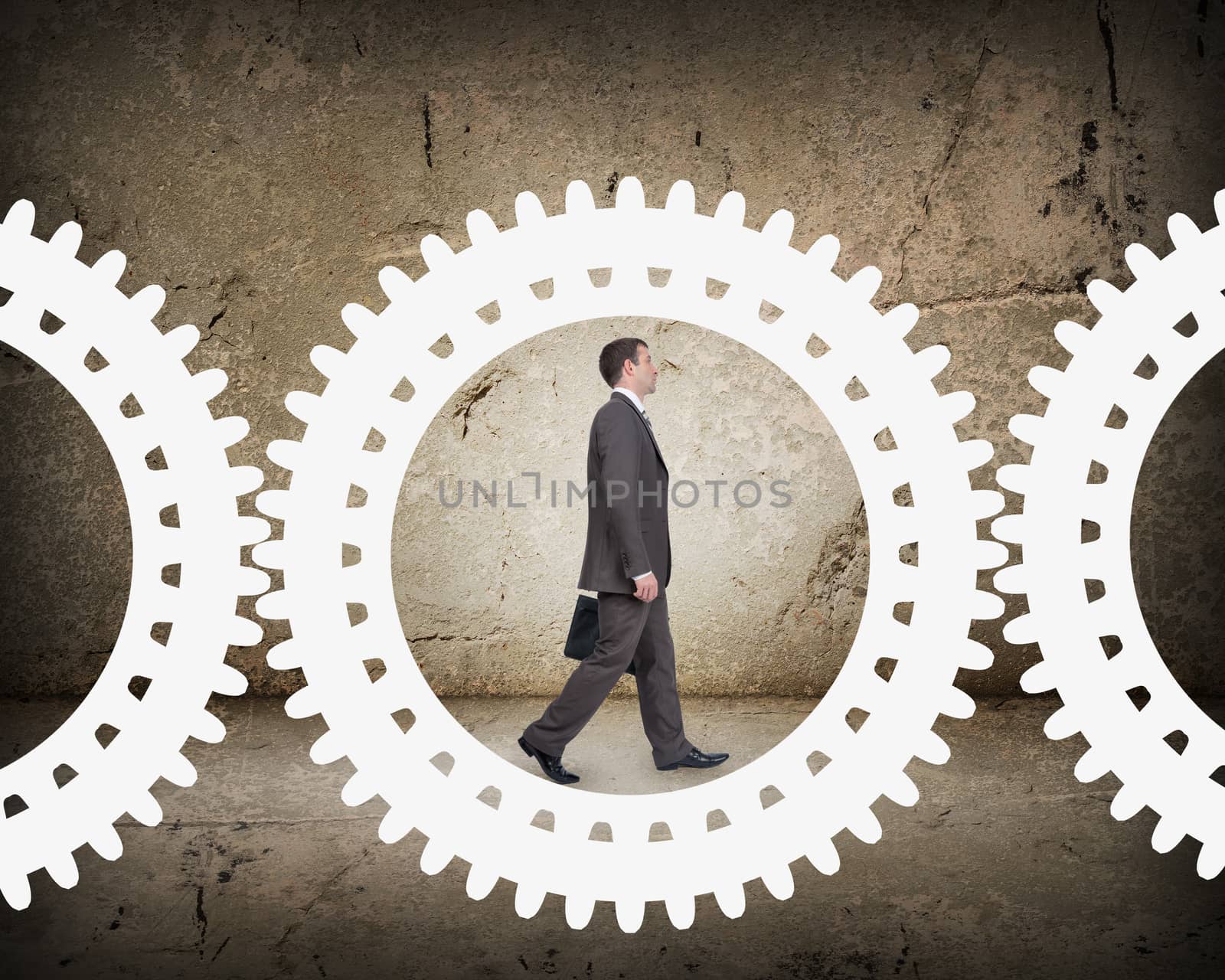 Businessman walking in cog wheel on abstract background