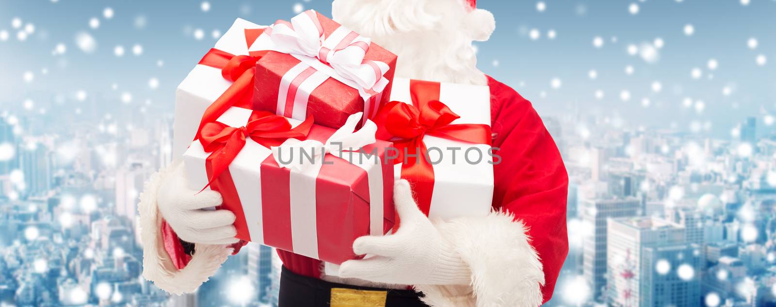 christmas, holidays and people concept - close up of santa claus with gift box over snowy city background