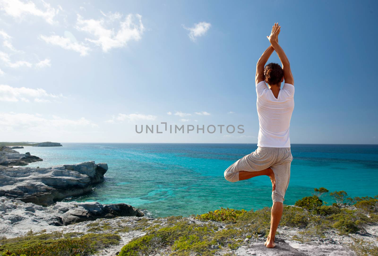 fitness, sport, people and lifestyle concept - young man making yoga exercises on beach from back