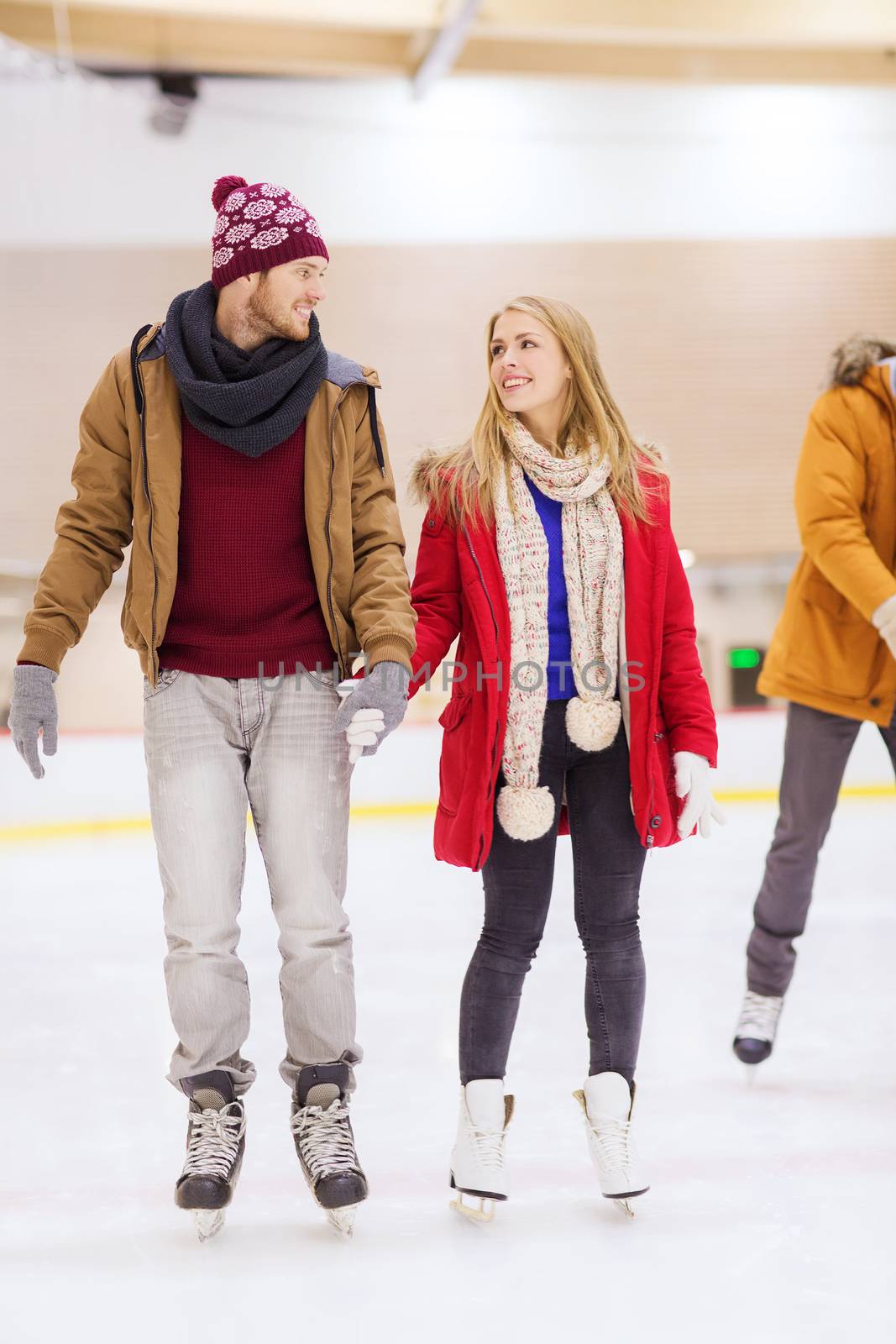 happy couple holding hands on skating rink by dolgachov