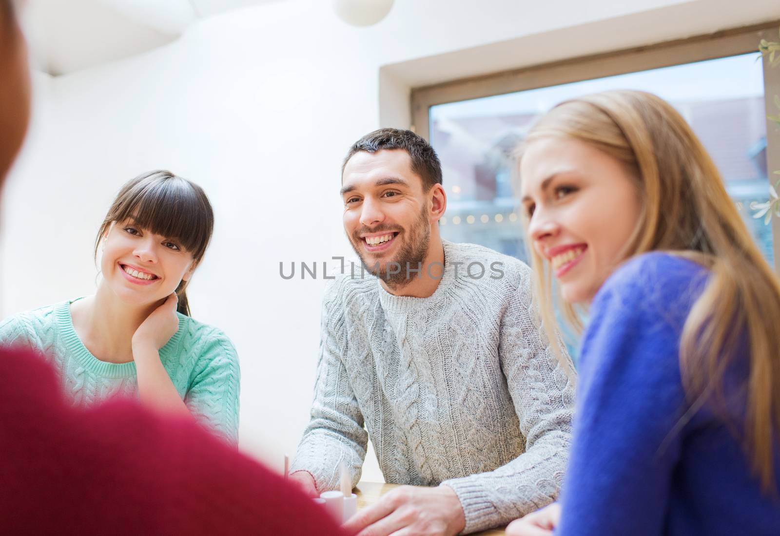 people, leisure, friendship and communication concept - group of happy friends meeting and talking