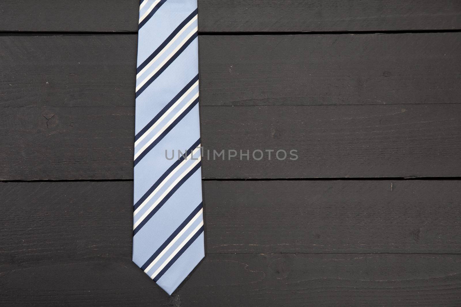 Striped business tie on dark wooden background by gigra