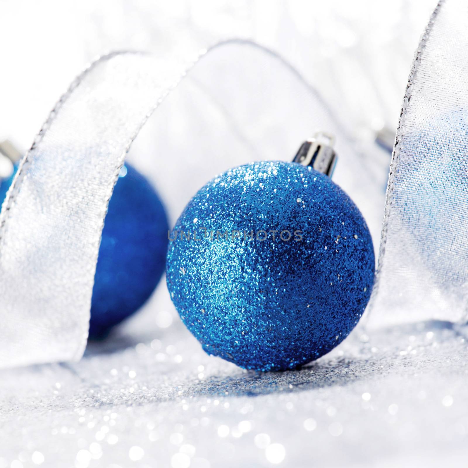 Blue Christmas balls and ribbon on abstract glitter silver background