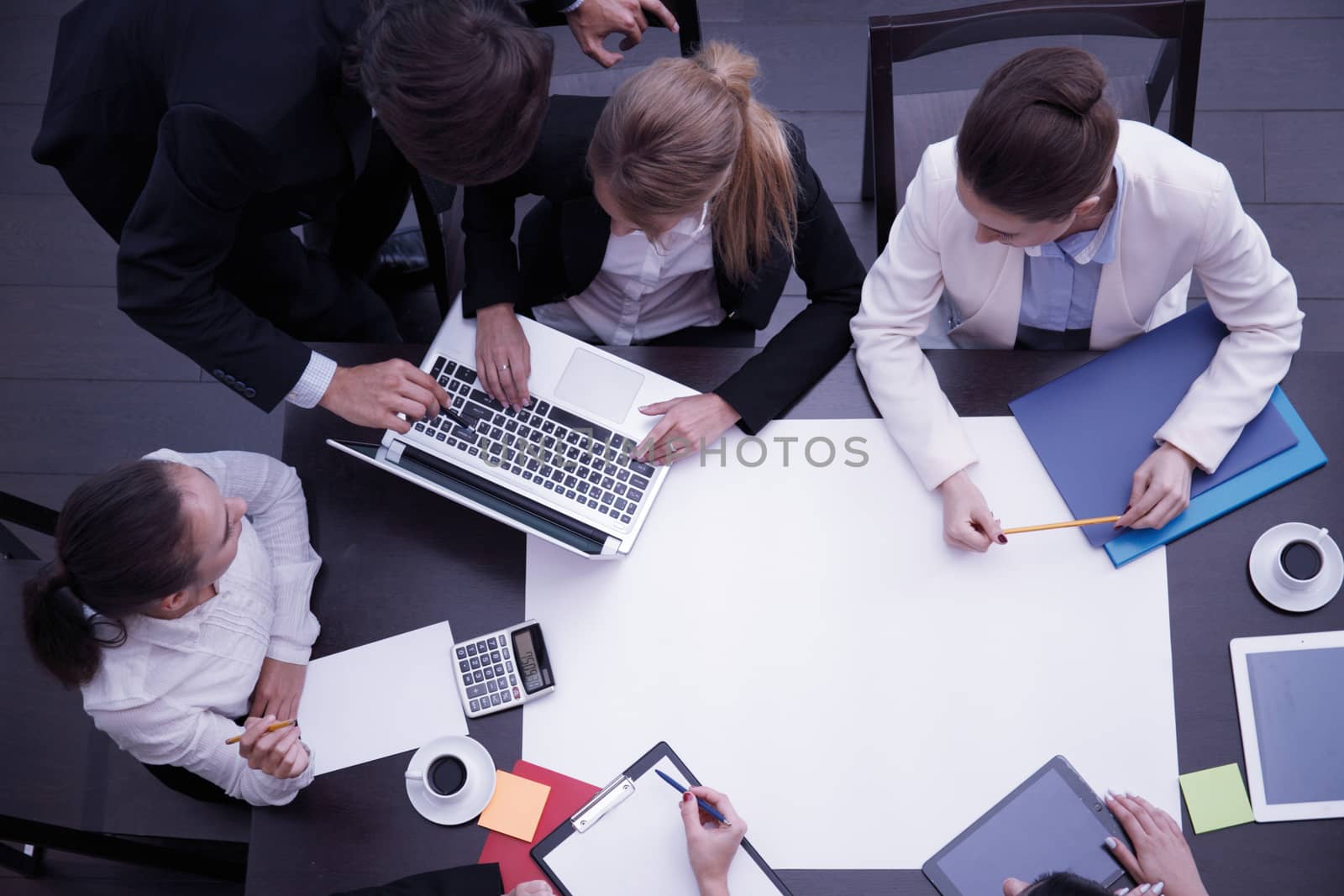 Business workplace with people, cup of coffee, digital tablet, smartphone, papers and various office objects on table