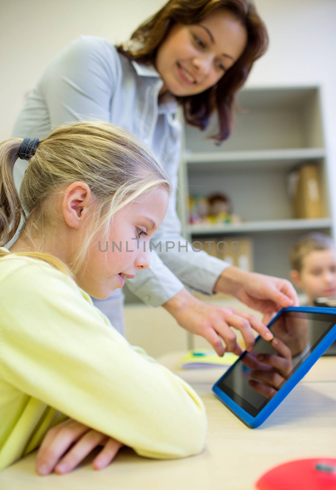 education, elementary school, learning, technology and people concept - little girl with teacher and tablet pc computer in classroom