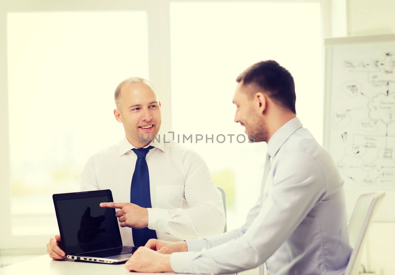 two smiling businessmen with laptop in office by dolgachov