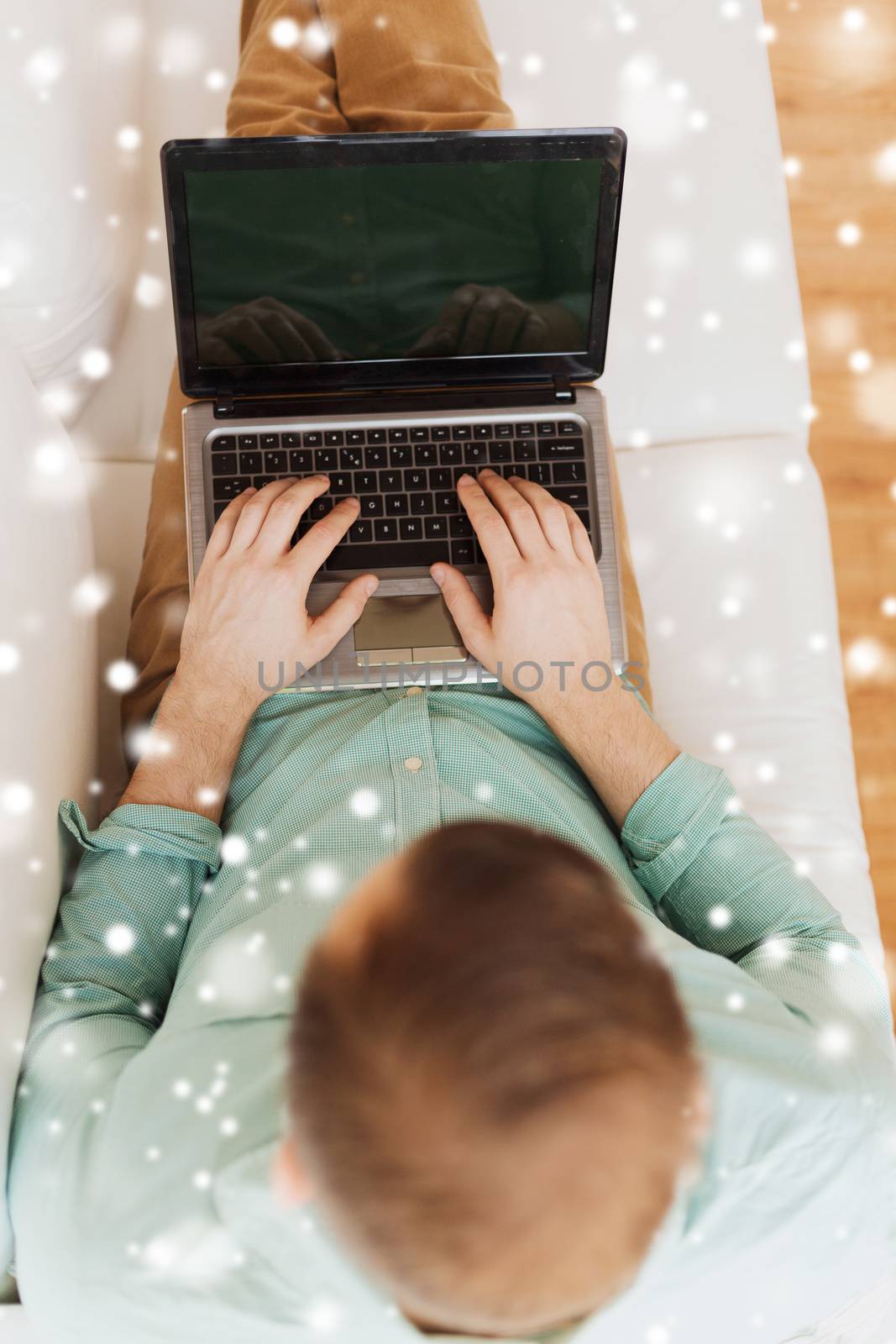 technology, leisure, advertisement and lifestyle concept - close up of man working with laptop computer and sitting on sofa at home