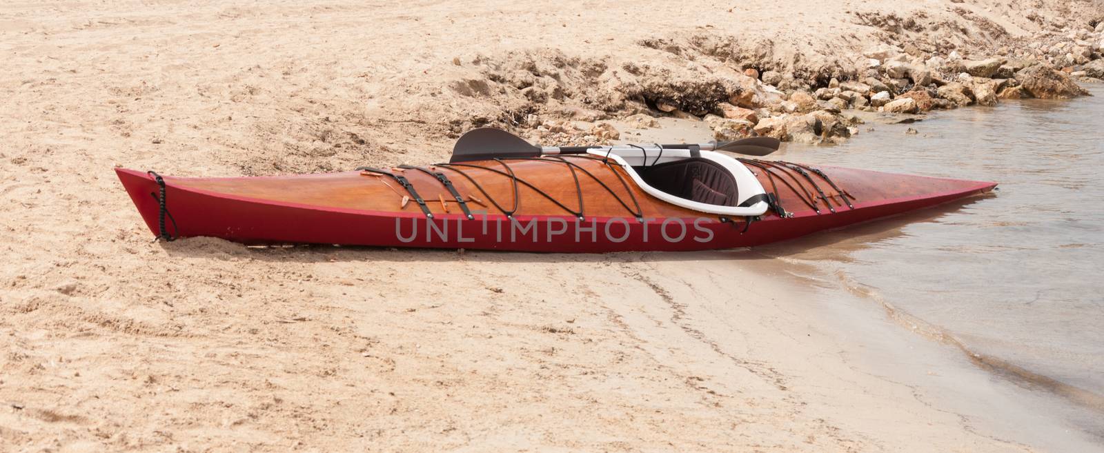 Wooden kayak on the sand and the sea