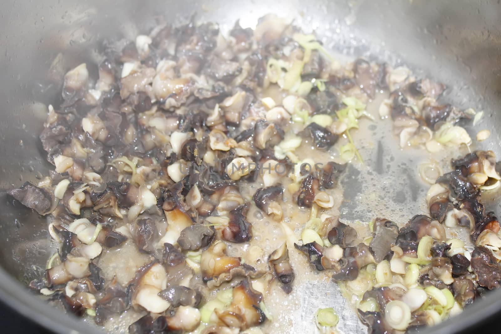 Closeup of eating the fried snails with stalks lemon grass 