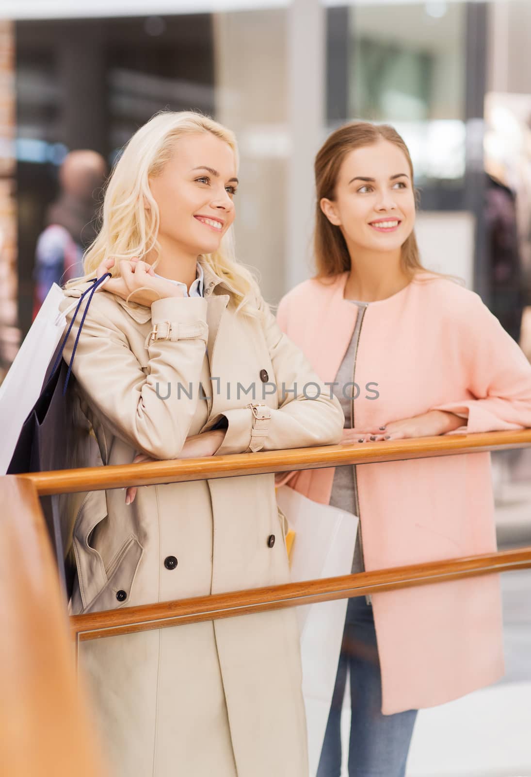 happy young women with shopping bags in mall by dolgachov
