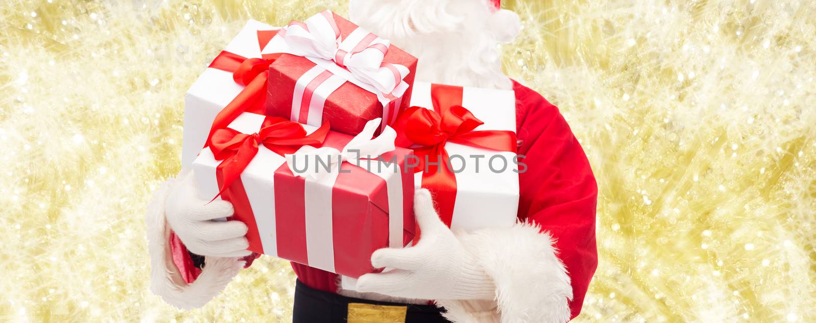 christmas, holidays and people concept - close up of santa claus with gift box over yellow lights background