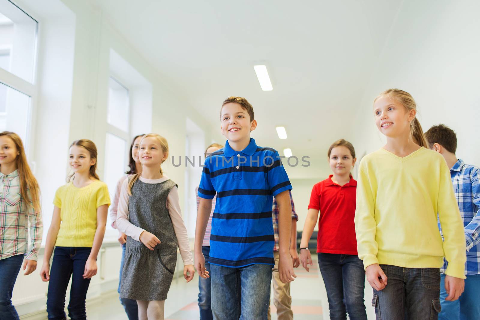 education, elementary school, drinks, children and people concept - group of smiling school kids walking in corridor