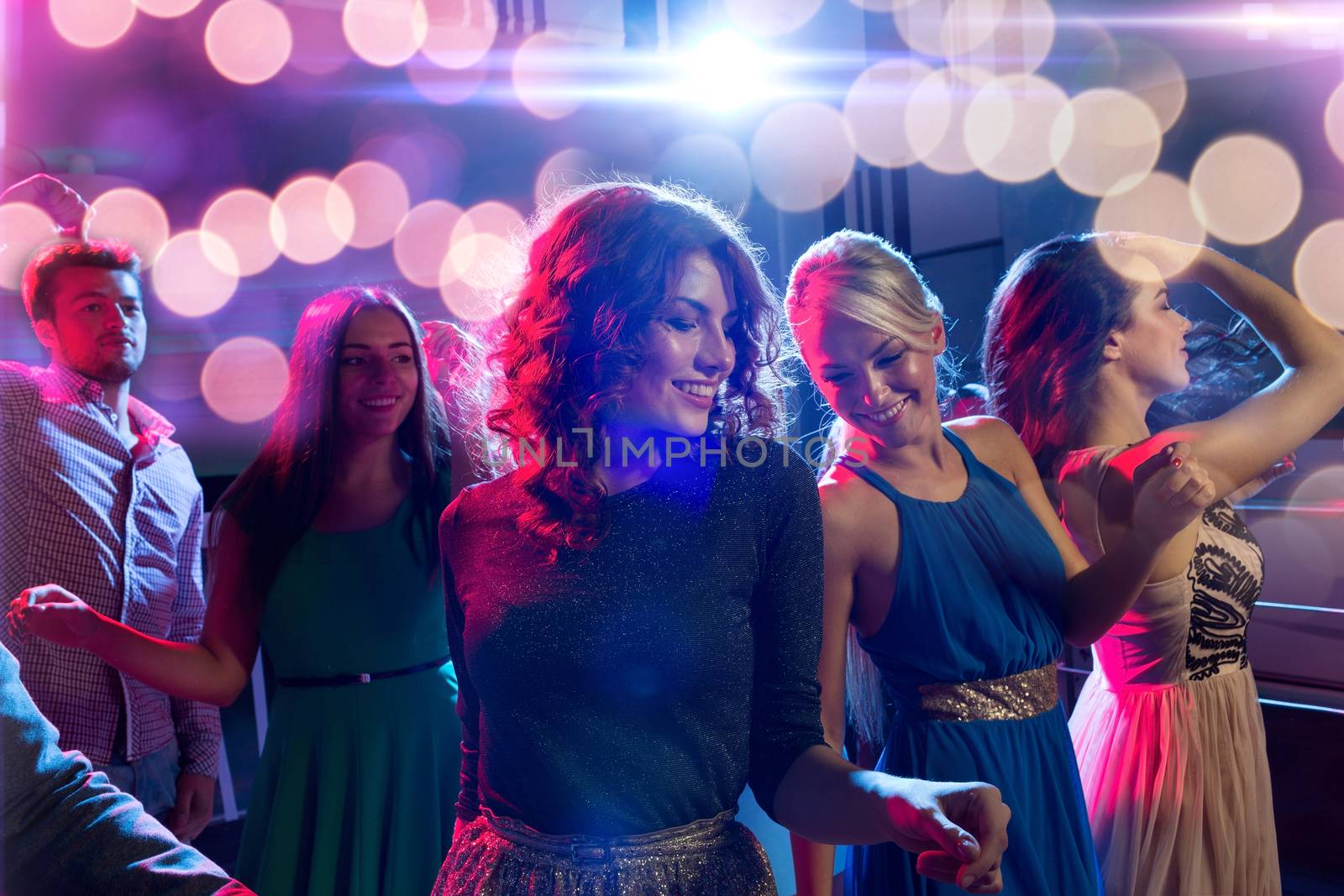 smiling friends dancing in club by dolgachov