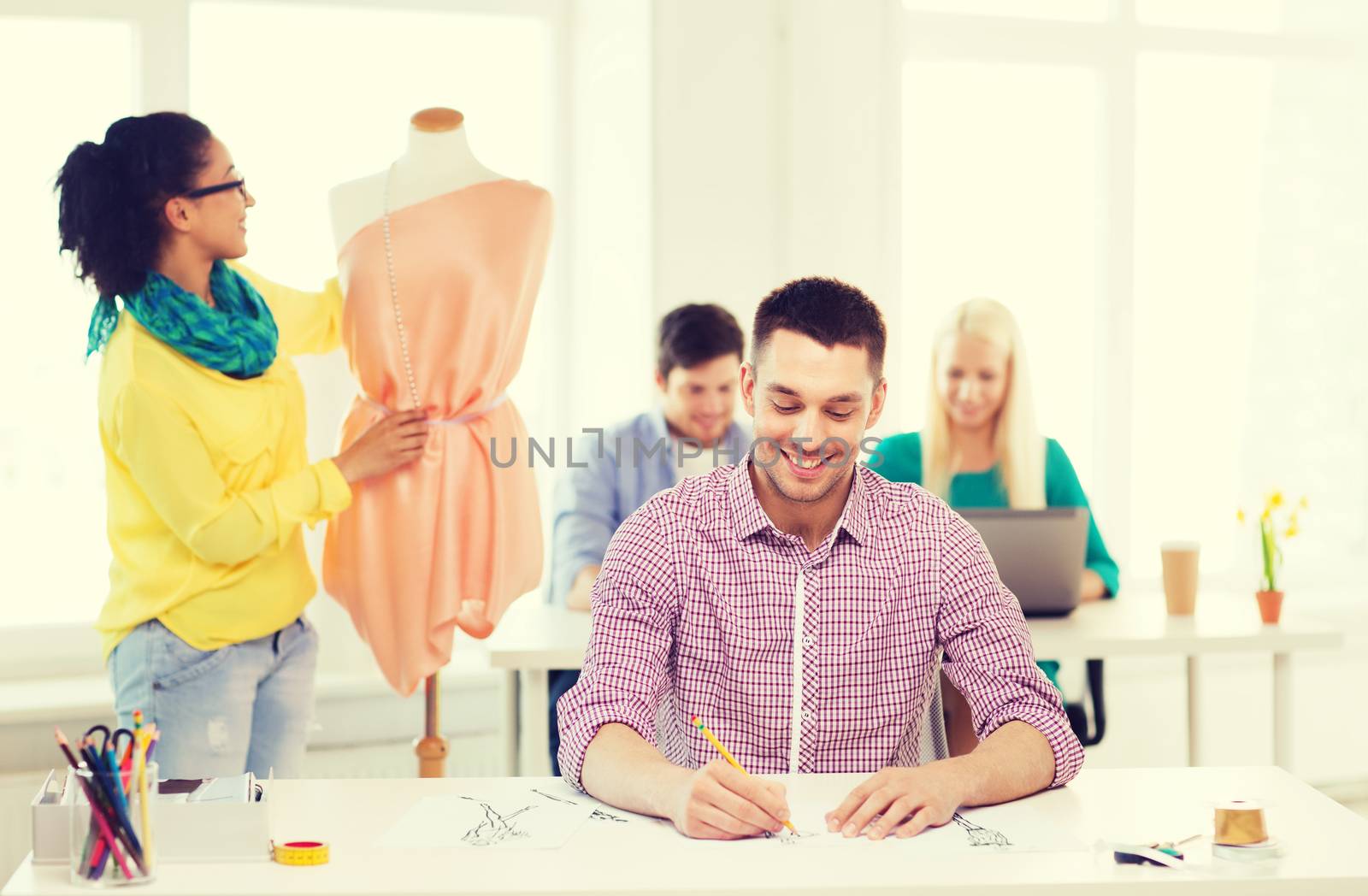smiling fashion designers working in office by dolgachov
