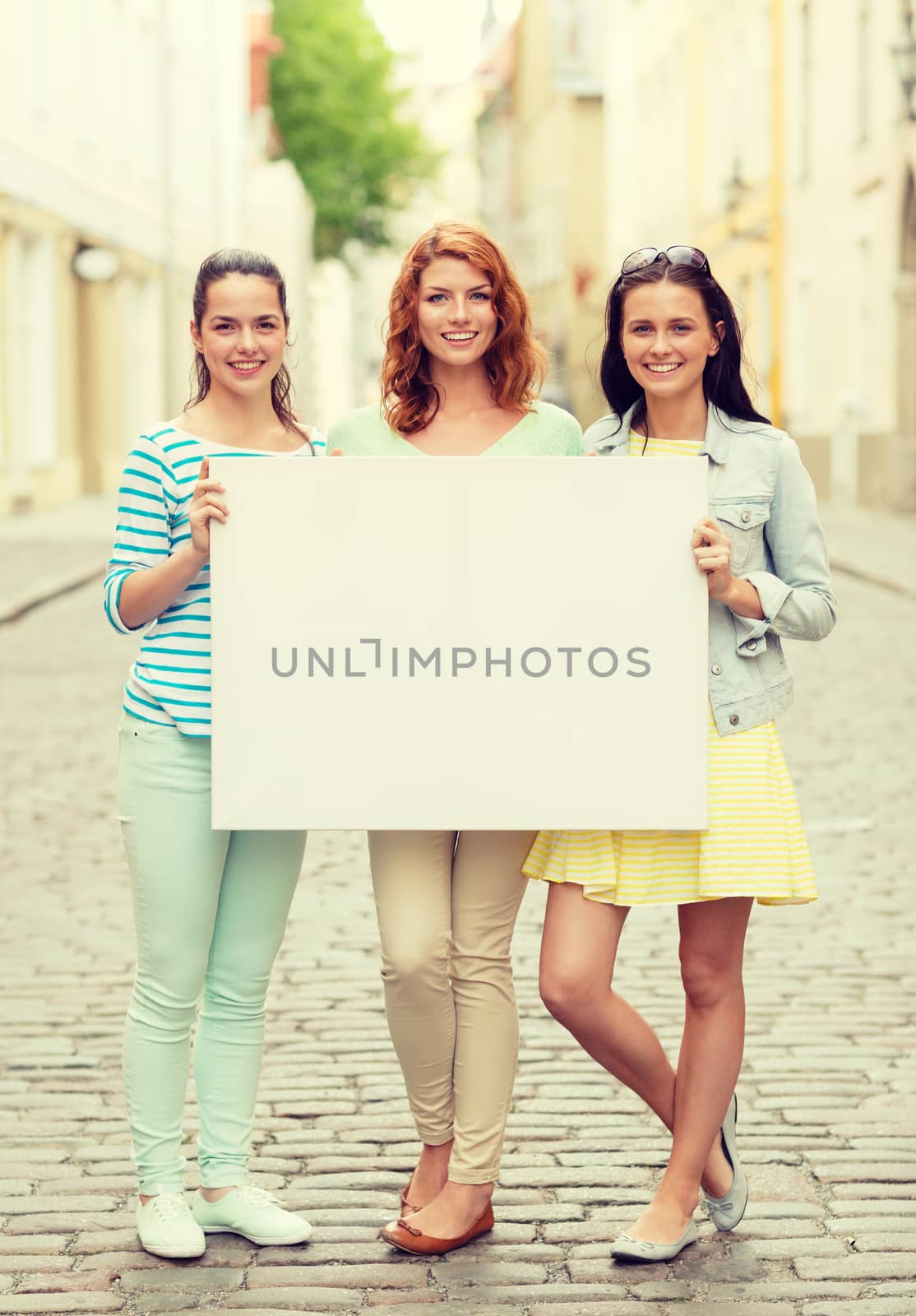 smiling teenage girls with blank billboard by dolgachov