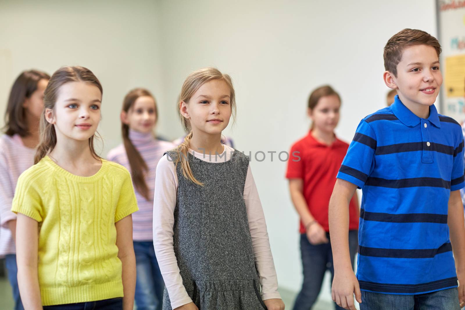 education, elementary school, drinks, children and people concept - group of smiling school kids walking in corridor