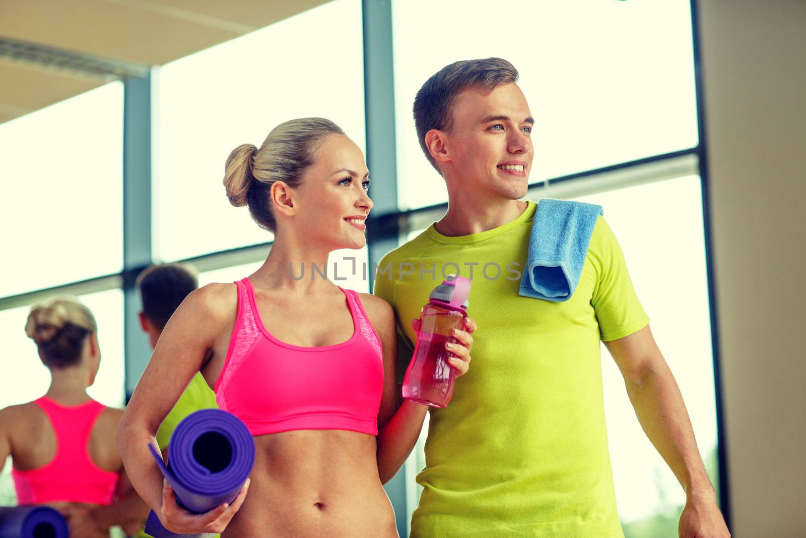smiling couple with water bottles in gym by dolgachov