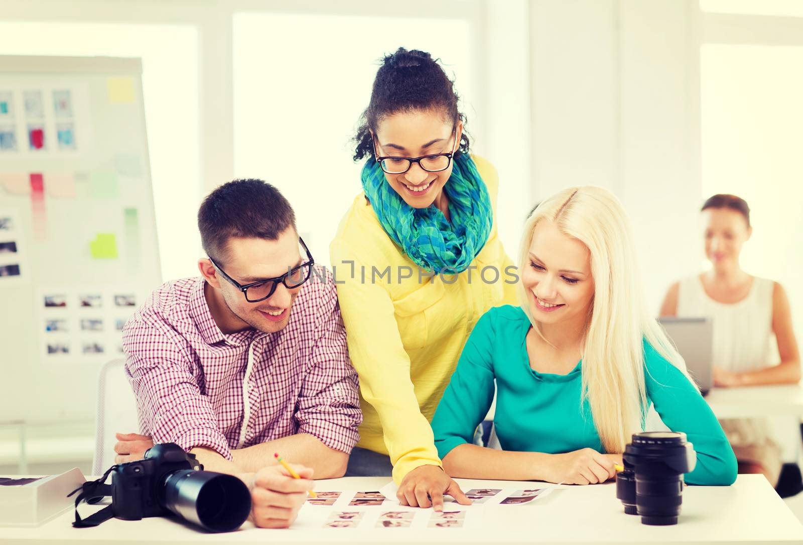 business, education, photography, office and startup concept - smiling creative team with printed photos working in office